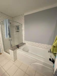 Bathroom featuring a white subway-tiled walk-in shower with a glass enclosure, adjacent to a large soaking bathtub, creating a clean and inviting spa-like atmosphere.